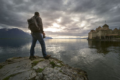 Rear view of man standing on rock against sky