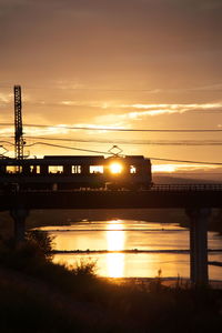 Bridge over river against sky during sunset