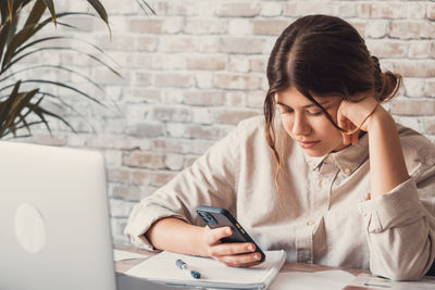 Young woman using mobile phone on table