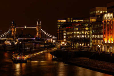 Illuminated tower bridge over thames river in city