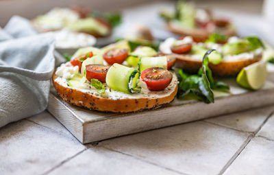 Bagels sandwich with cream cheese, cottage cheese, avocado, tomatoes, cucumbers and salad leaves