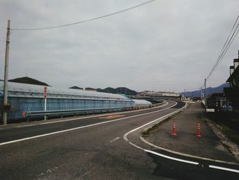 Vehicles on road against cloudy sky