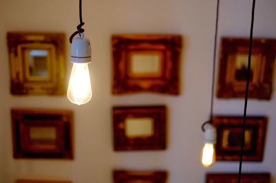 Close-up of illuminated electric bulb hanging at home