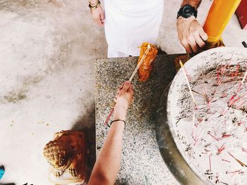 Cropped hands of woman holding incense sticks at temple