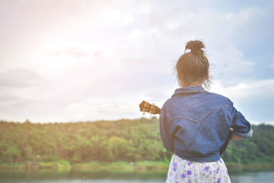 Rear view of a girl standing against sky