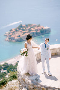 Rear view of couple holding umbrella