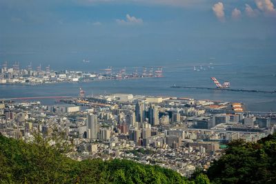 High angle view of city by sea against sky