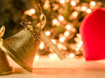 Bells and heart shape against illuminated christmas decorations