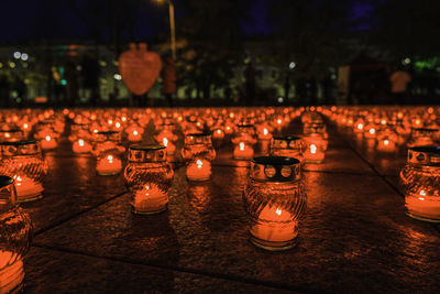 Burning church candles in red transparent chandeliers