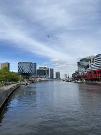 City buildings by river against sky