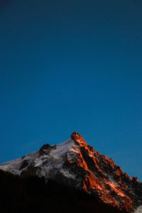 Low angle view of volcanic mountain against blue sky