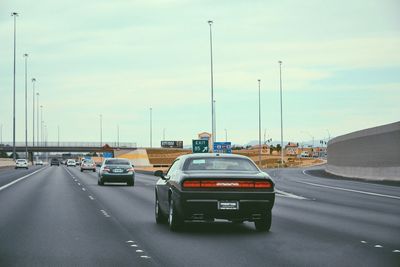 Cars on road in city against sky