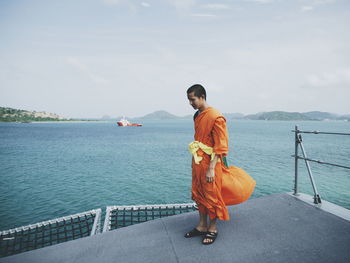 Side view of monk on boat deck sailing in sea