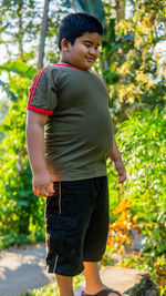 Boy looking away while standing against plants