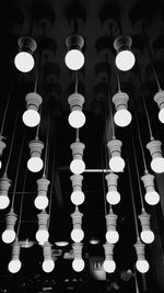 Low angle view of illuminated light bulb hanging against black background