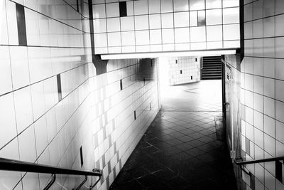 Empty footpath amidst tile wall