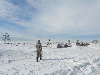 Rear view of man walking on snow covered landscape