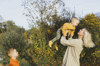 Happy boy looking at mother carrying son in autumn