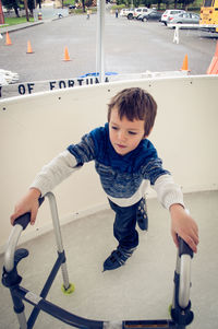 High angle view of boy ice skating while holding frame walker