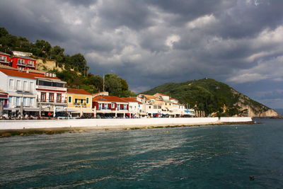 Buildings by sea against sky