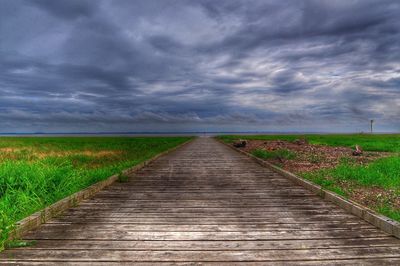 View of field against cloudy sky