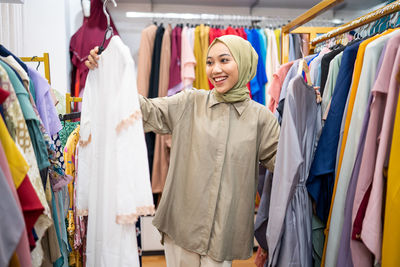 Smiling woman in hijab choosing clothes at store