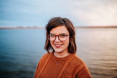 Center portrait of a woman wearing glasses near a lake