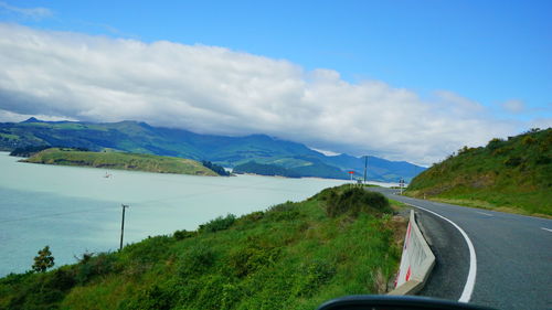 Road amidst trees and mountains against sky