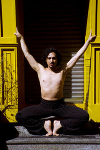 Full length portrait of shirtless man exercising on sunny day