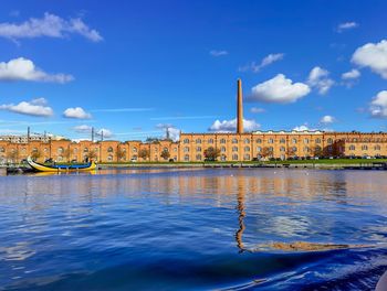 River by buildings against blue sky