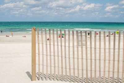 Deck chairs on beach against sky