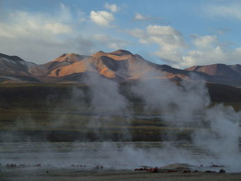 Geyser emitting from volcanic mountain against sky