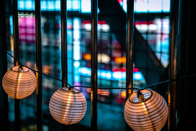 Close-up of illuminated lanterns hanging on glass window