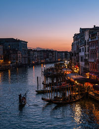 Illuminated buildings in city against sky at sunset