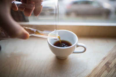 Cropped image of person pouring coffee in cup