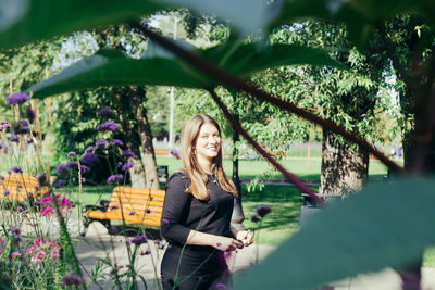 Portrait of smiling young woman standing against plants