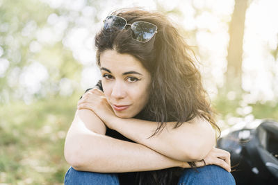 Young woman in nature sitting resting on her motorcycle route with her helmet behind