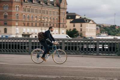 Man riding bicycle on building in city