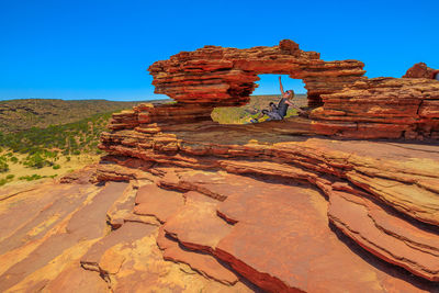 Woman sitting on rock formation at kalbarri national park 