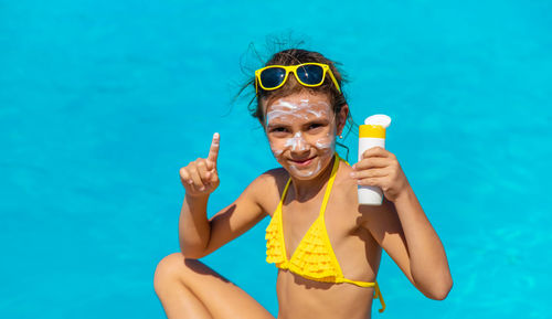 Portrait of girl applying suntan lotion by pool