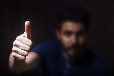 Close-up of man gesturing thumbs up in darkroom