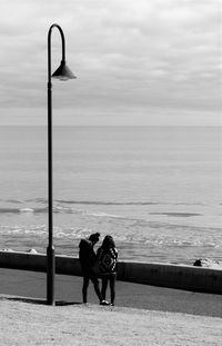 Rear view of couple standing by sea against sky