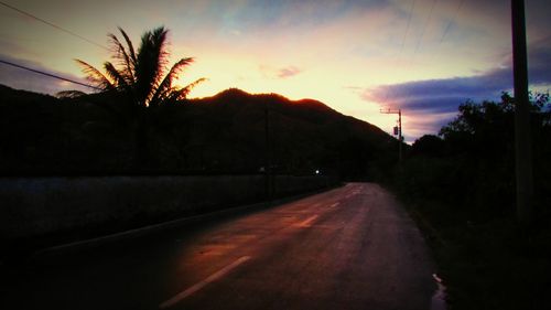 Road amidst trees against sky during sunset