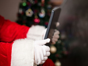 Cropped image of santa claus holding digital tablet