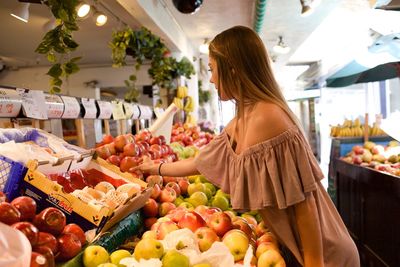 Side view of woman buying fruits at market