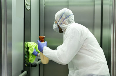 Coronavirus. worker disinfecting hospital elevator to avoid contagion.