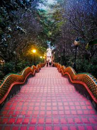 Illuminated steps amidst trees in park at dusk