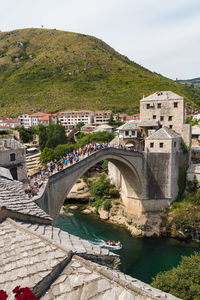 Bridge over river by buildings against sky