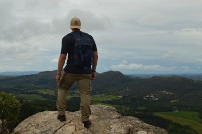 Rear view of man standing on mountain against sky