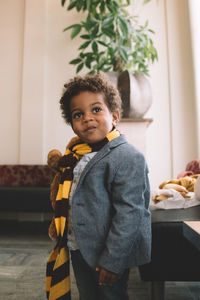 Cute boy in suit looking away while standing at home